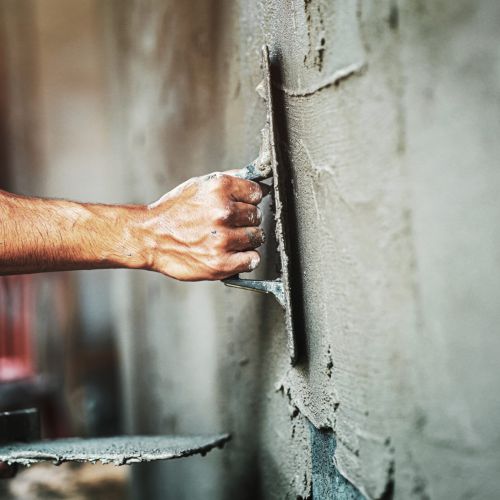 closeup hand of worker plastering cement at wall for building house