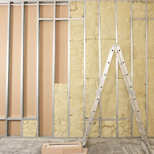 Ladder near wall with metal studs and insulation material indoors